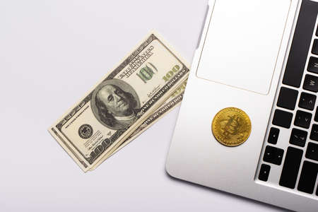KYIV, UKRAINE - APRIL 26, 2022: Top view of dollars near bitcoin on laptop on white backgroundのeditorial素材