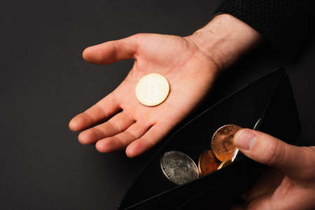 KYIV, UKRAINE - APRIL 26, 2022: Cropped view of man holding golden bitcoin and wallet isolated on...