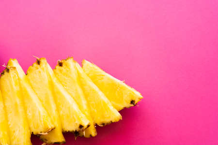 Top view of tasty cut pineapple on pink surfaceの写真素材