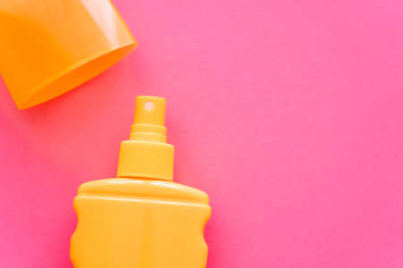 Top view of sunscreen and cap on pink surface