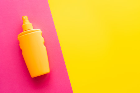 Top view of sunblock on pink and yellow background