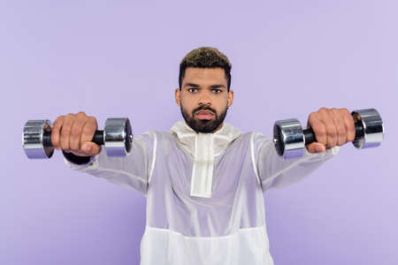 bearded african american man exercising with dumbbells isolated on purpleの写真素材