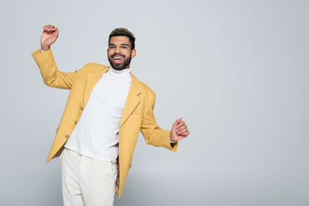 excited african american man in stylish yellow blazer posing isolated on greyの写真素材