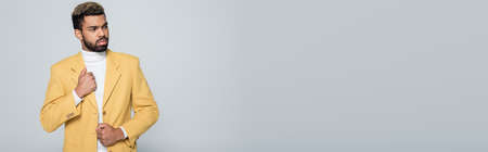 stylish african american man in yellow blazer posing isolated on grey, bannerの写真素材
