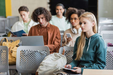 young woman with digital tablet listening lecture near multicultural studentsの写真素材