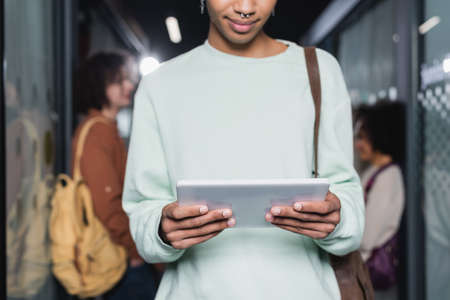 cropped view of african american student with digital tablet on blurred backgroundの写真素材
