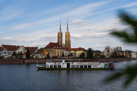WROCLAW, POLAND - APRIL 18, 2022: Boat on river water with buildings on embankment at background