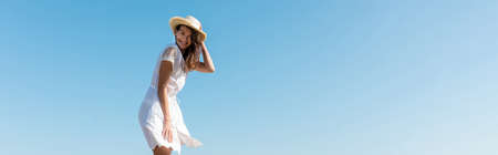 Young woman in white dress and sun hat smiling at camera with sky at background, bannerの写真素材