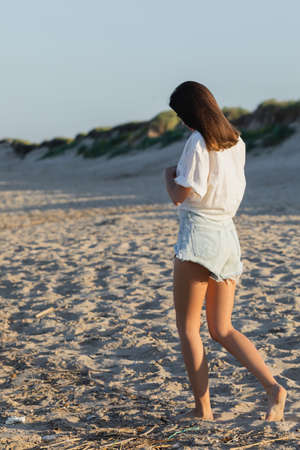 Young woman in denim shorts walking on beachの写真素材