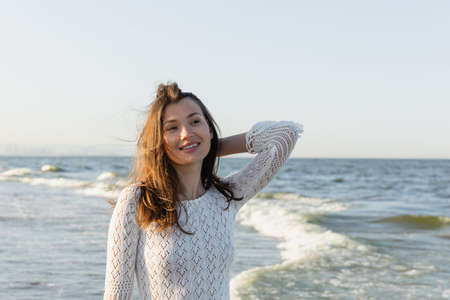 Portrait of young brunette woman looking away near blurred sea