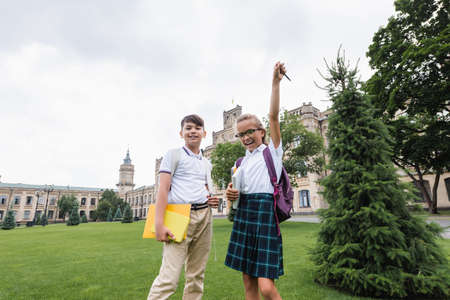 Interracial schoolkids with notebooks looking at camera on lawn outdoorsの写真素材