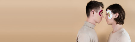 Side view of young same sex couple with petal on faces on beige, bannerの写真素材