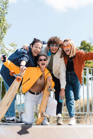 excited interracial skaters looking at camera and screaming outdoorsの写真素材
