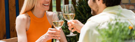 Cropped view of positive couple toasting with wine in outdoor cafe, bannerの写真素材