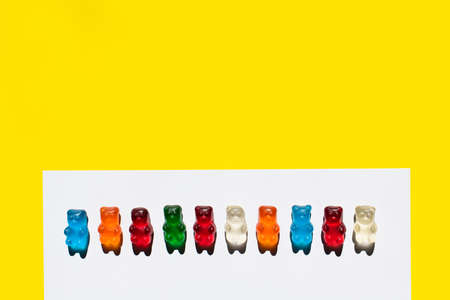 Top view of row from gummy bears on white and yellowの写真素材