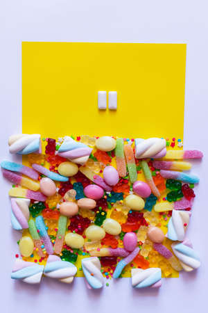 Top view of chewing gums near colorful sweets on white and yellow surfaceの写真素材