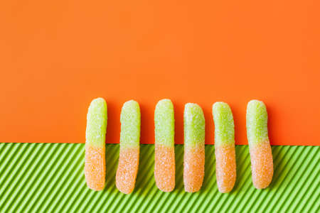 Top view of jelly sweets on orange and green surface