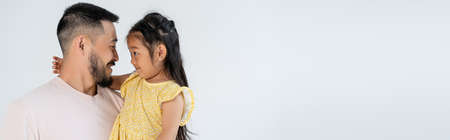 side view of happy father and daughter looking at each other isolated on grey, bannerの写真素材