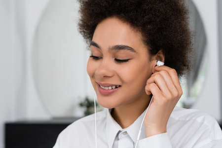 happy african american woman listening music in wired earphonesの写真素材
