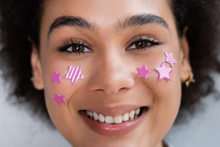 portrait of happy african american woman with decorative purple stars on cheeksの写真素材
