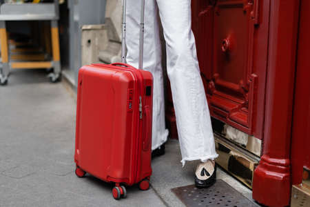 Cropped view of suitcase near traveler on urban street in Parisの写真素材