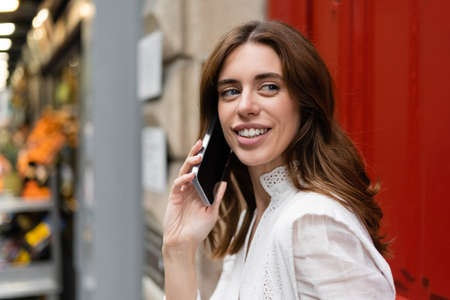 Positive brunette woman talking on smartphone outdoors in Paris