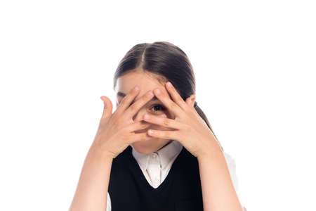 Schoolkid covering face and looking at camera isolated on whiteの写真素材