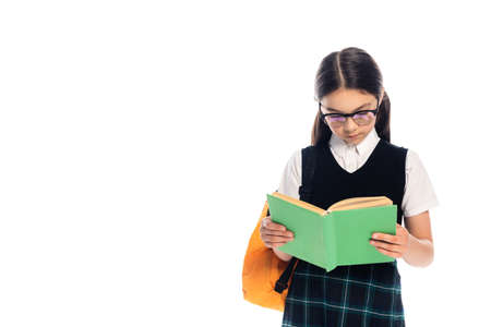 Preteen schoolgirl in eyeglasses reading book isolated on whiteの写真素材