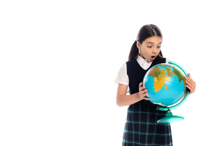 Amazed preteen pupil looking at globe isolated on whiteの写真素材