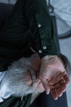 top view of unhappy retired man with beard lying on couch while suffering crisisの写真素材