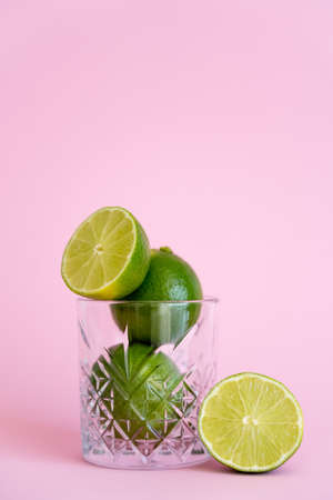 green and fresh limes in faceted glass on pink backgroundの写真素材