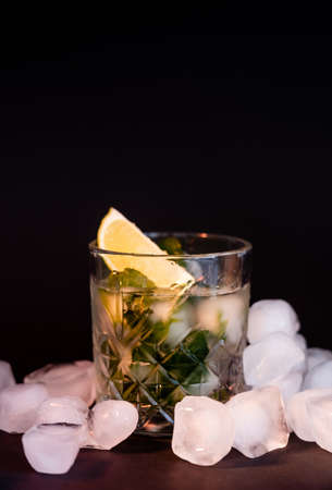 cool faceted glass with mojito near ice cubes on blackの写真素材