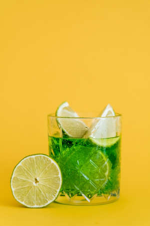 sliced limes in glass with sparkling mojito drink on yellowの写真素材