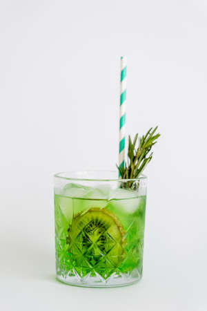 cool faceted glass with kiwi mojito, ice cubes and rosemary isolated on whiteの写真素材
