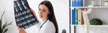 Brunette doctor holding mri scan in clinic, banner