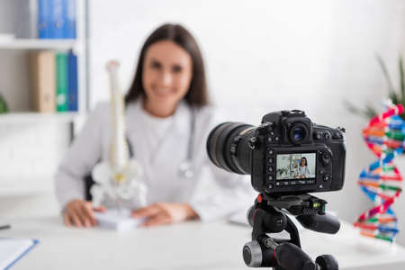 Blurred doctor holding spinal model near digital camera in hospitalの写真素材