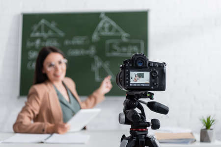 Digital camera near blurred teacher in classroomの写真素材