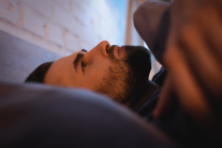 Worried man with sleep disorder lying on bed at nightの写真素材