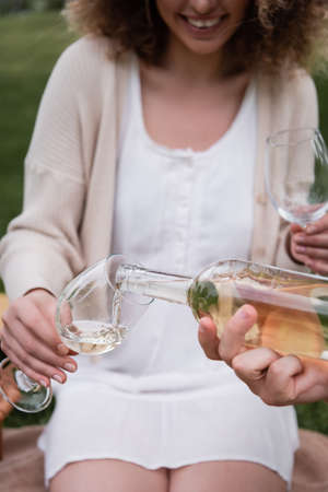 cropped view of man pouring wine in glass near happy girlfriend