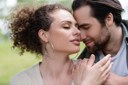portrait of pleased woman with closed eyes hugging with bearded man
