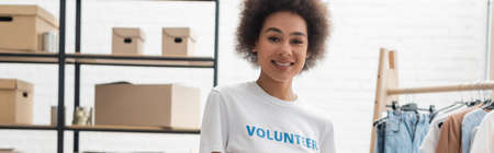 pretty african american woman smiling at camera in volunteer center, bannerの写真素材