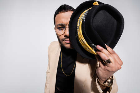 eastern hip hop performer covering half of face with fedora hat isolated on greyの写真素材