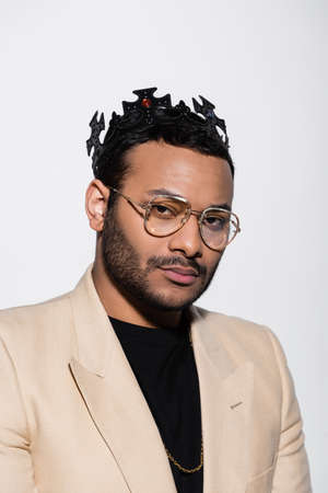 eastern hip hop performer in crown and eyeglasses isolated on grey