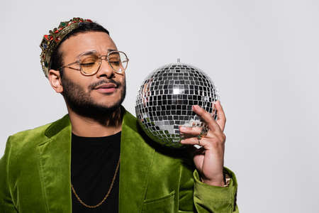 eastern hip hop performer in green velvet blazer and crown holding disco ball isolated on greyの写真素材