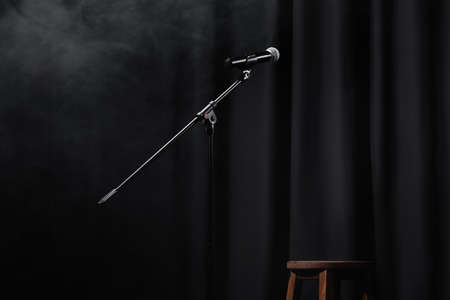 microphone near curtain and wooden chair on stage with smokeの写真素材