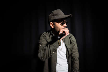 middle east hip hop singer in cap and sunglasses singing into microphone on blackの写真素材