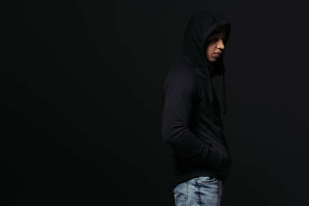 Side view of african american hooligan in hoodie standing isolated on blackの写真素材