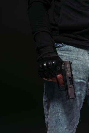 Cropped view of african american hooligan holding handgun isolated on blackの写真素材