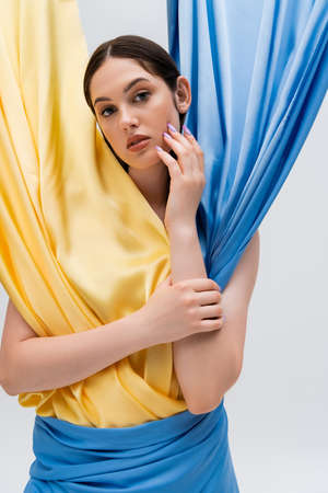 pretty woman in ukrainian blue and yellow dress looking at camera isolated on greyの写真素材