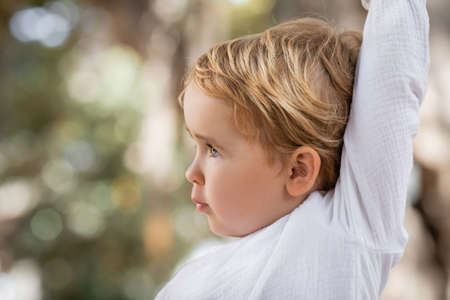 Side view of toddler girl with raising hand outdoorsの写真素材